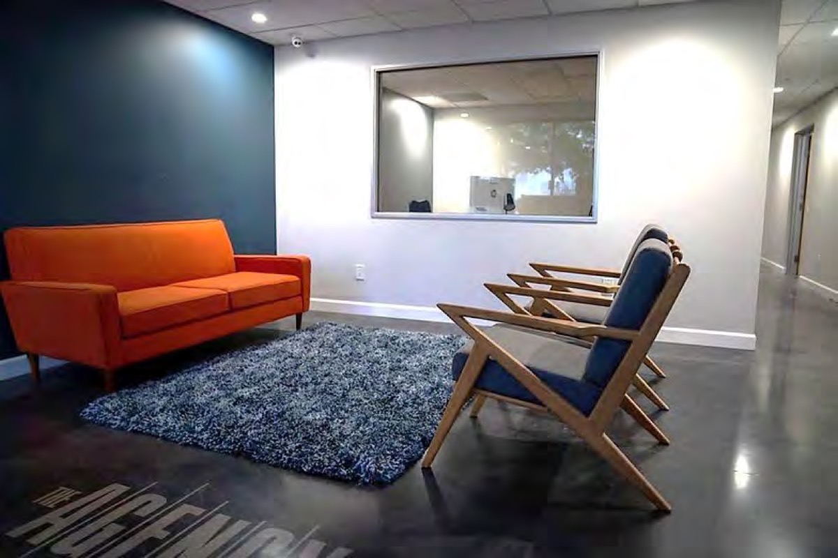 Lobby lounge with an orange sofa and wood armchairs by the windows