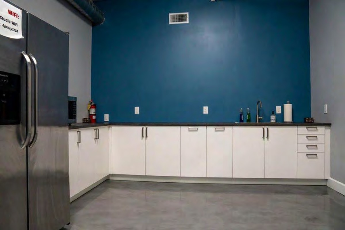 Kitchenette with a stainless refrigerator and white cabinets