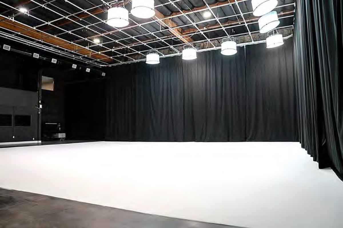 Black drapes enclosing the stage, white floor left clean