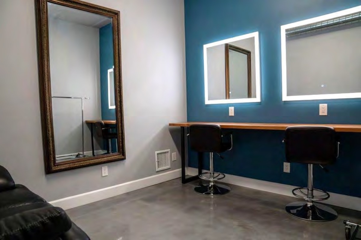 Makeup room with two lit mirrors and stools