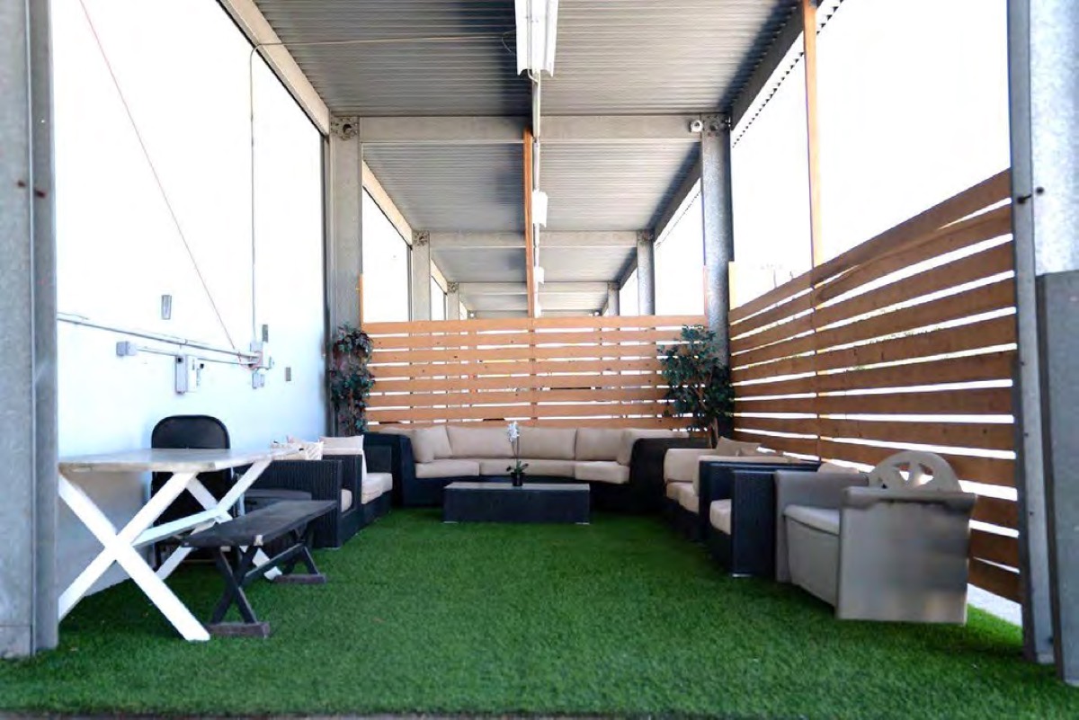 Covered outdoor lounge with turf, sofas, and a picnic table