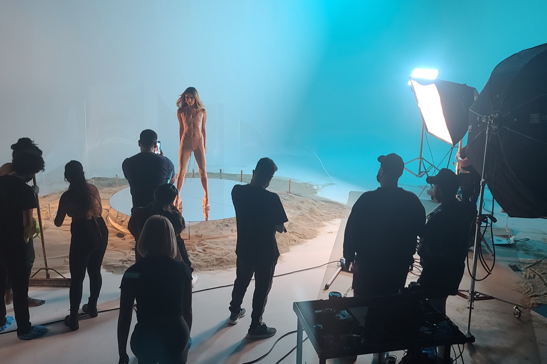 A dancer on a sand set under teal light with crew watching