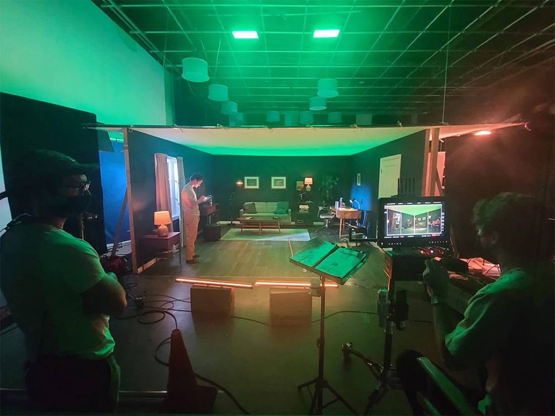 A living-room set lit green with a monitor and crew in the foreground